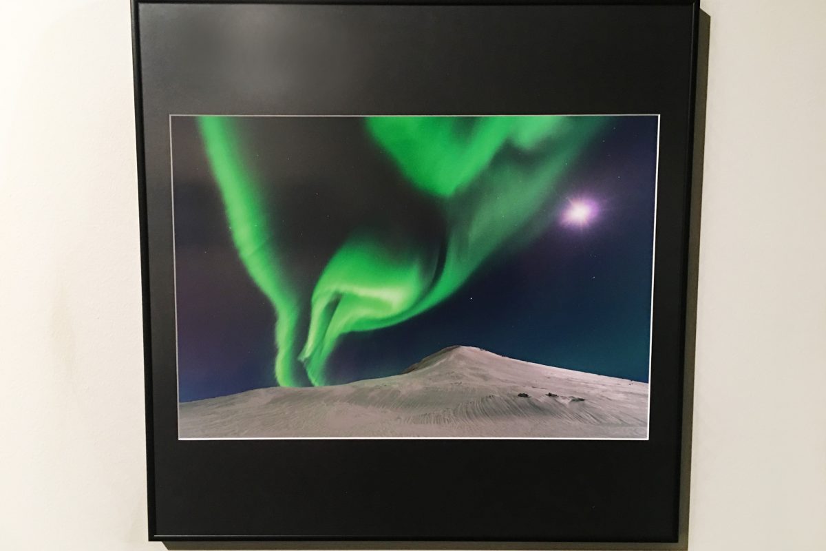 Photograph of Northern lights displayed on white wall.