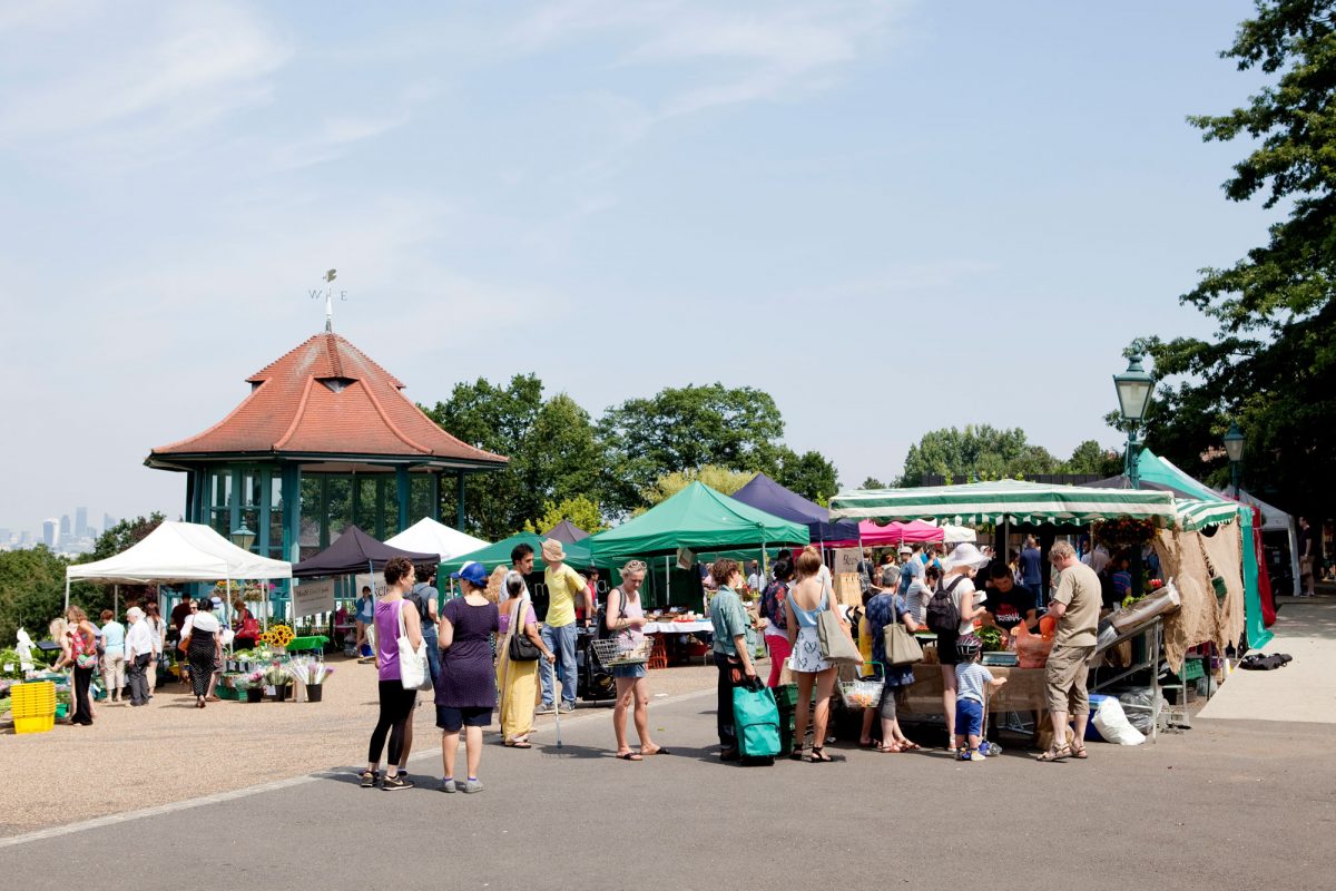 Market stalls in a terrace outdoors next to a bandstand.