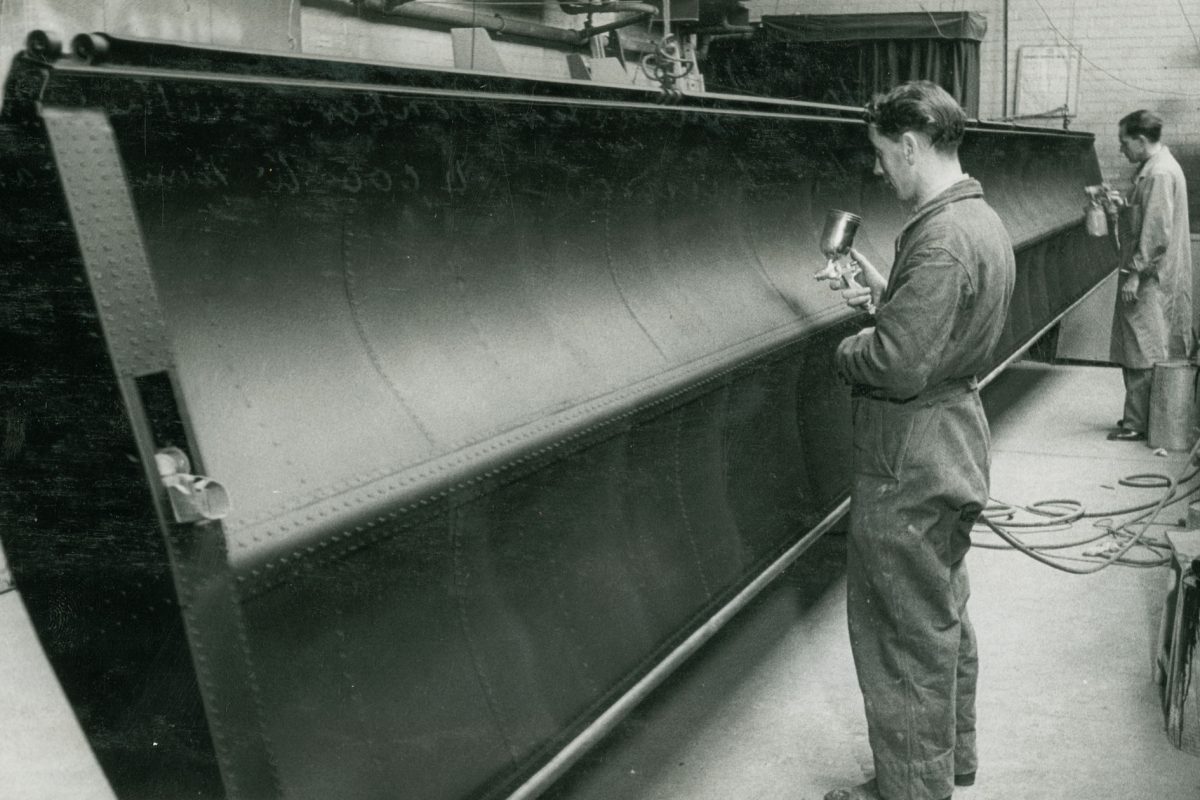 Black and white image of man working on door.