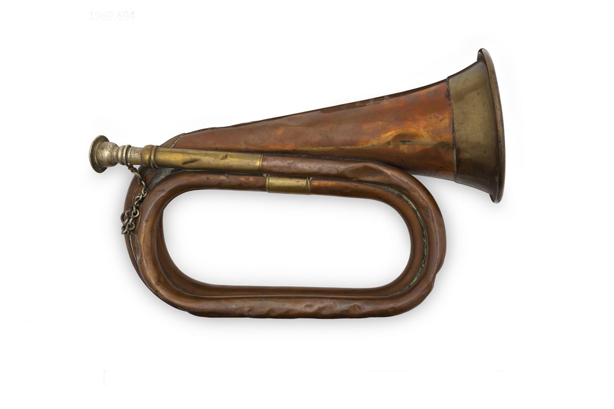 Wind instrument shaped like a curved horn, made from brass. The instrument is on a white background