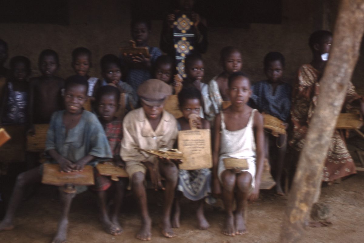 A group of boys sitting on a bench holding a document.