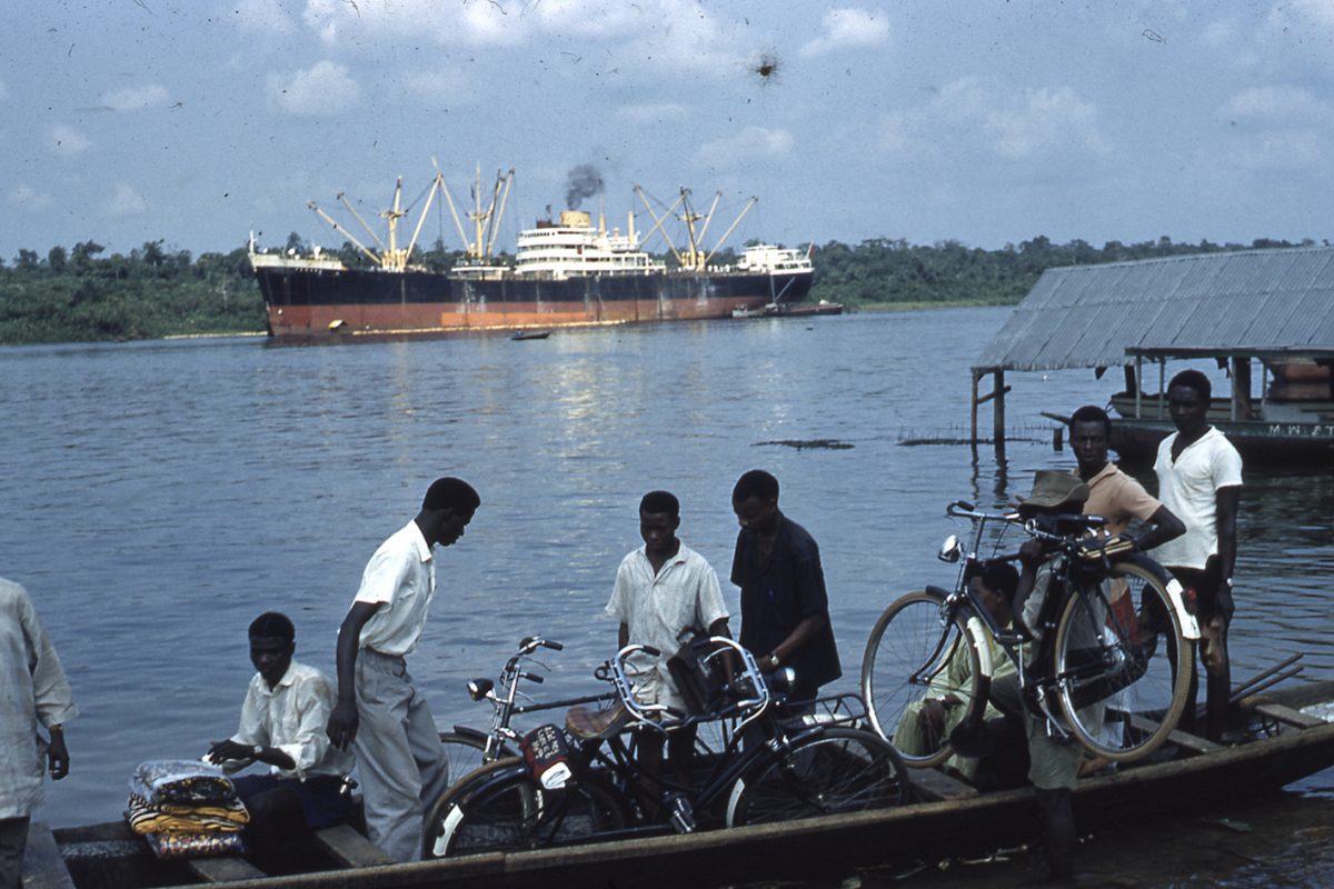 A group of boys on a canoe on the river with bikes.