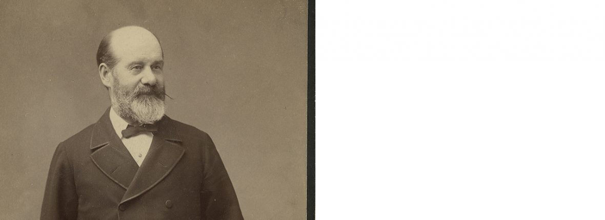 Black and white portrait of man in long black coat and bowtie