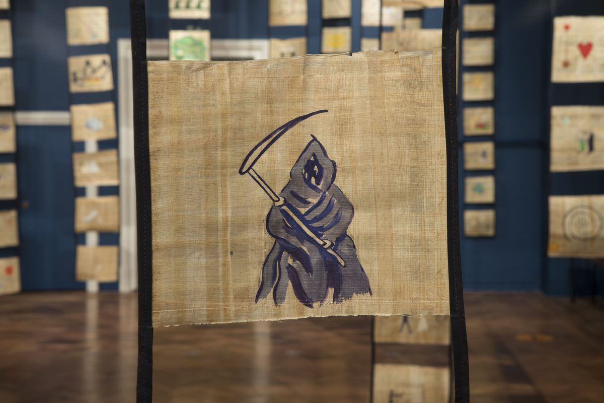 Close up of scroll with image of hooded figure carrying a scythe