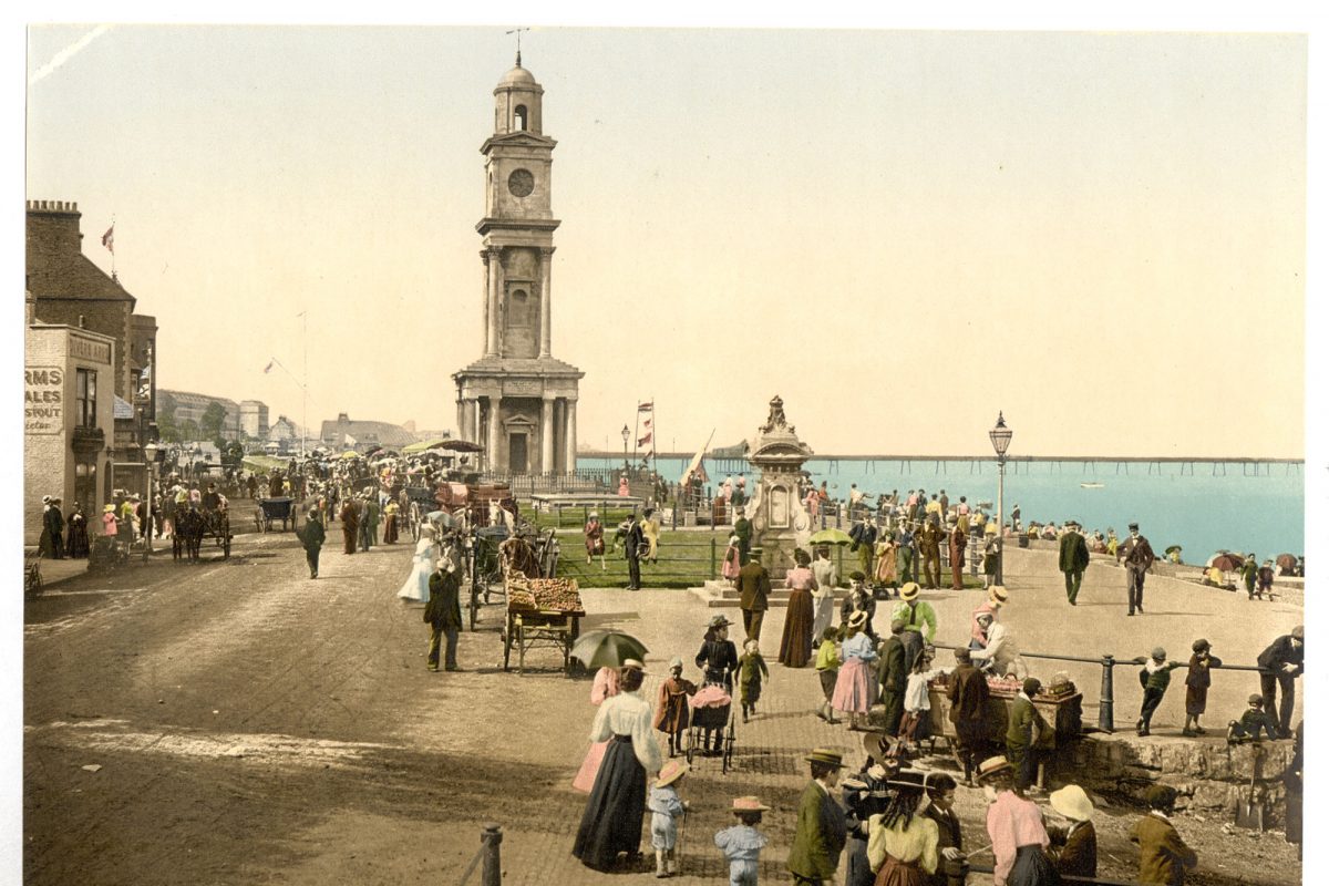 A colourised postcard of a victorian sea front with clock tower