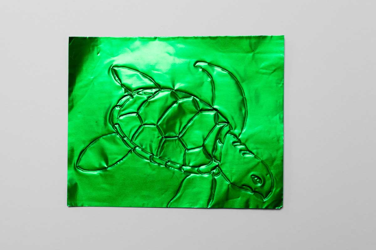 The outline of a turtle on green shiny paper