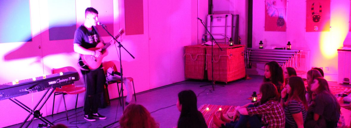 A man performs to a small audience at a Horniman Late