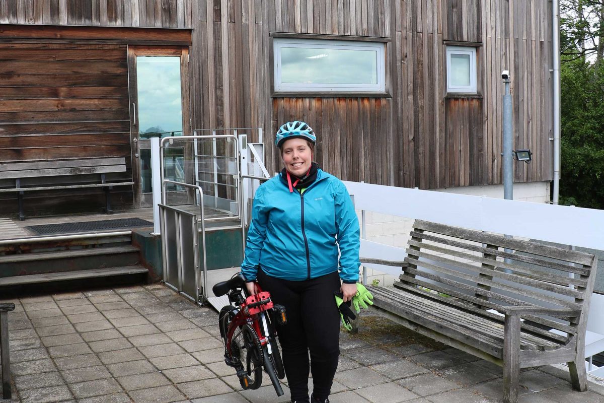 Charlotte stands next to her folded bike