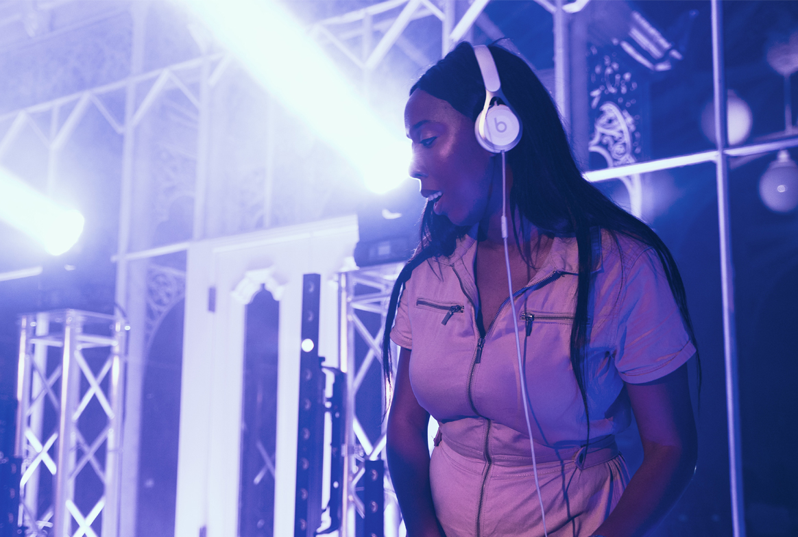 A woman wear headphones as she DJ's in the conservatory