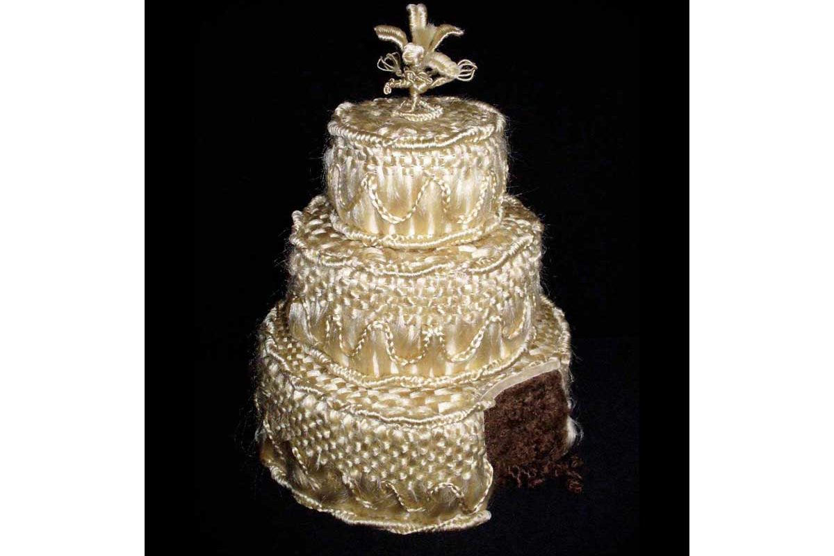 White wedding cake with a slice cut out of it to reveal it's made of brown hair