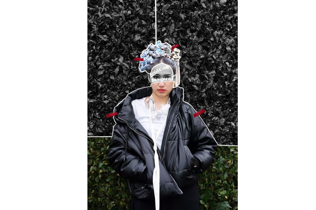 A woman wearing a white shirt and black puffer jacket looks at the camera with her hands in her pockets. She is wearing a flowery crown style headpiece. Across the top half of her face is written 'black is beautiful' and the top section of the image is in black and white.