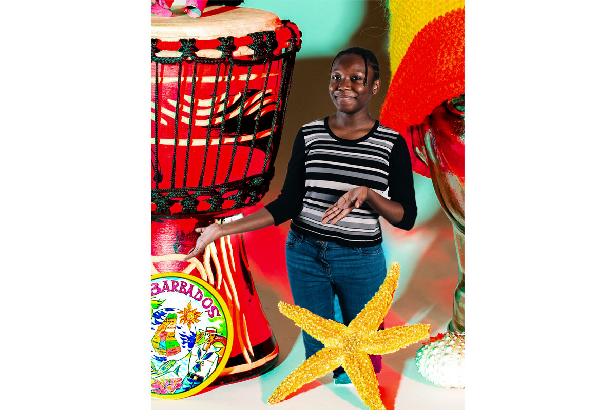 Woman standing with starfish at her feet and a drum behind her