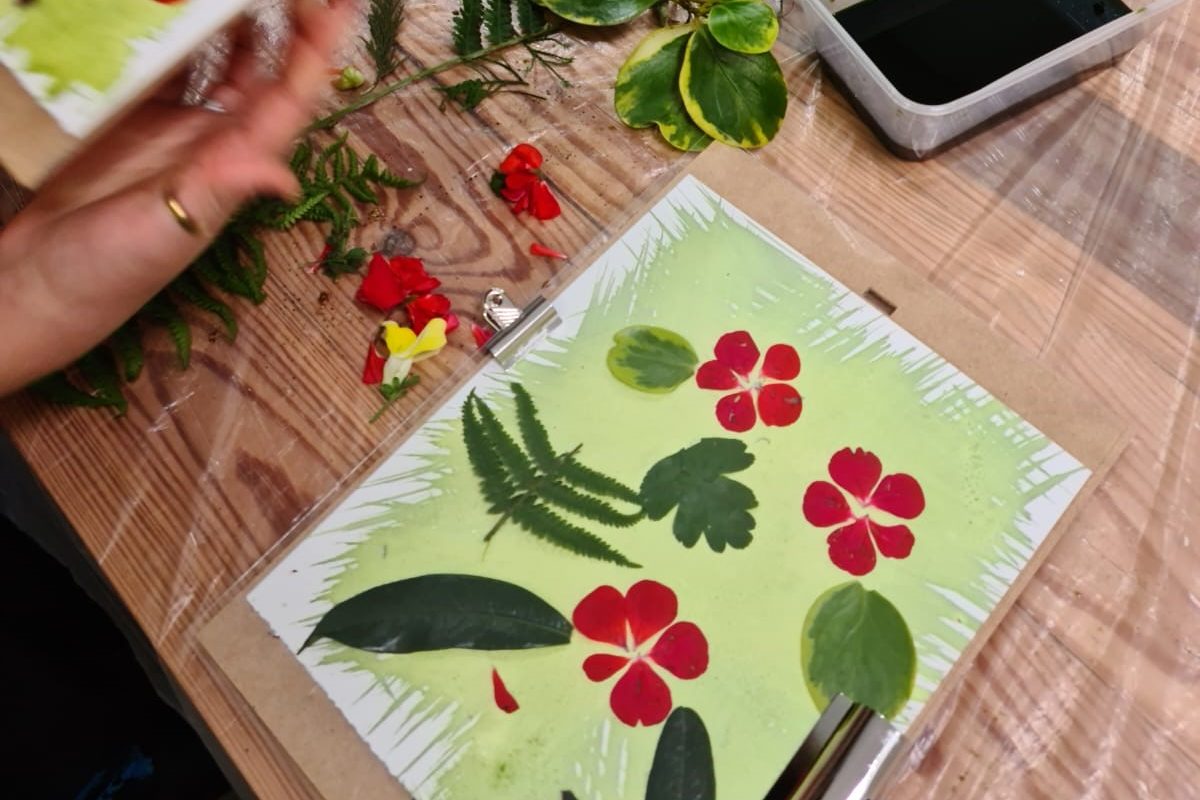 Flowers and leaves sit on top of colourful paper in a workshop