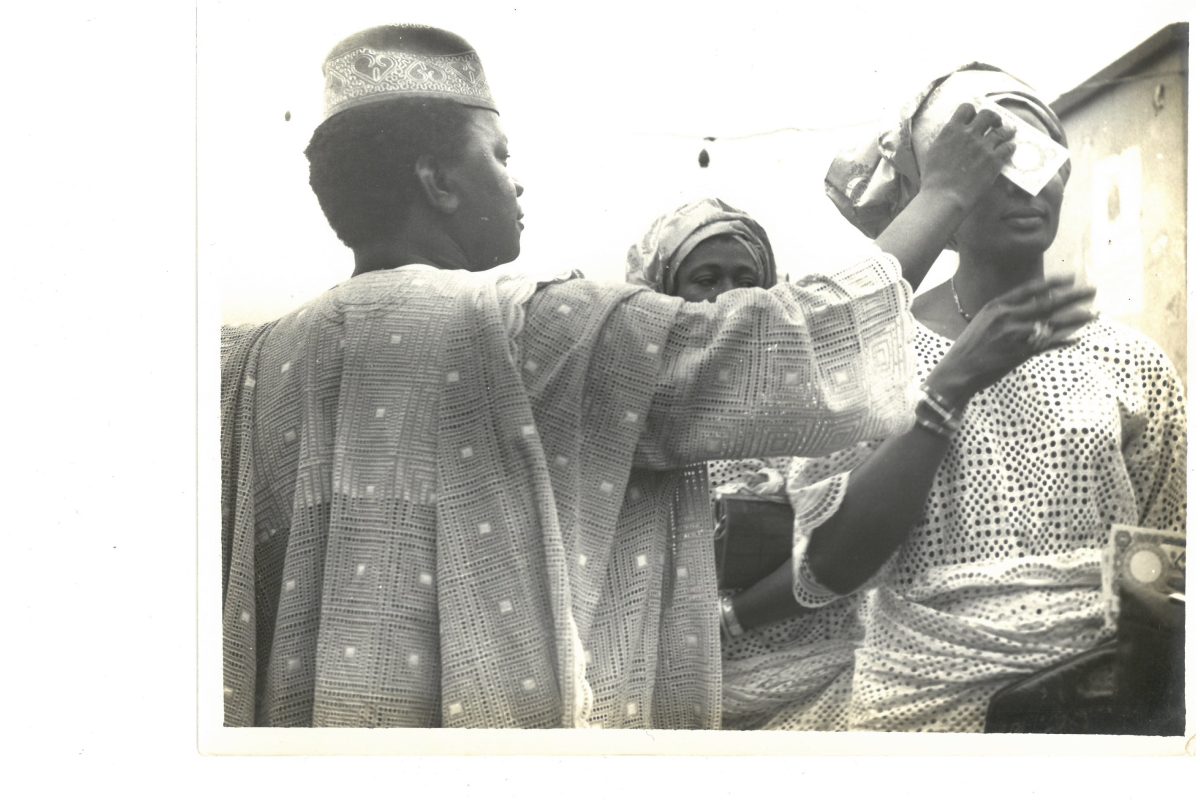 Abiola's father places Naira on her mother's head to display his wealth and show love and respect for her.