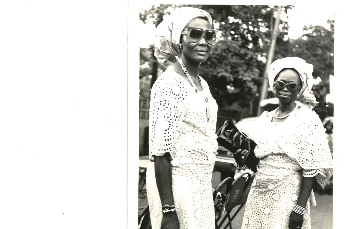 Black and white archive photo of two women wearing traditional yoruba outfits and sunglasses